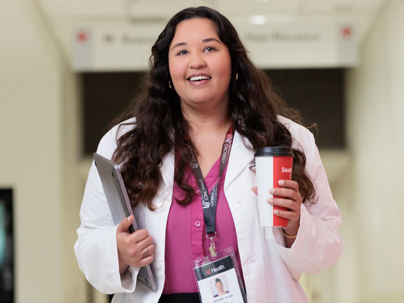 A mother works on her laptop as she holds her child on her lap