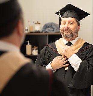 Male graduate adjusting tie in mirror