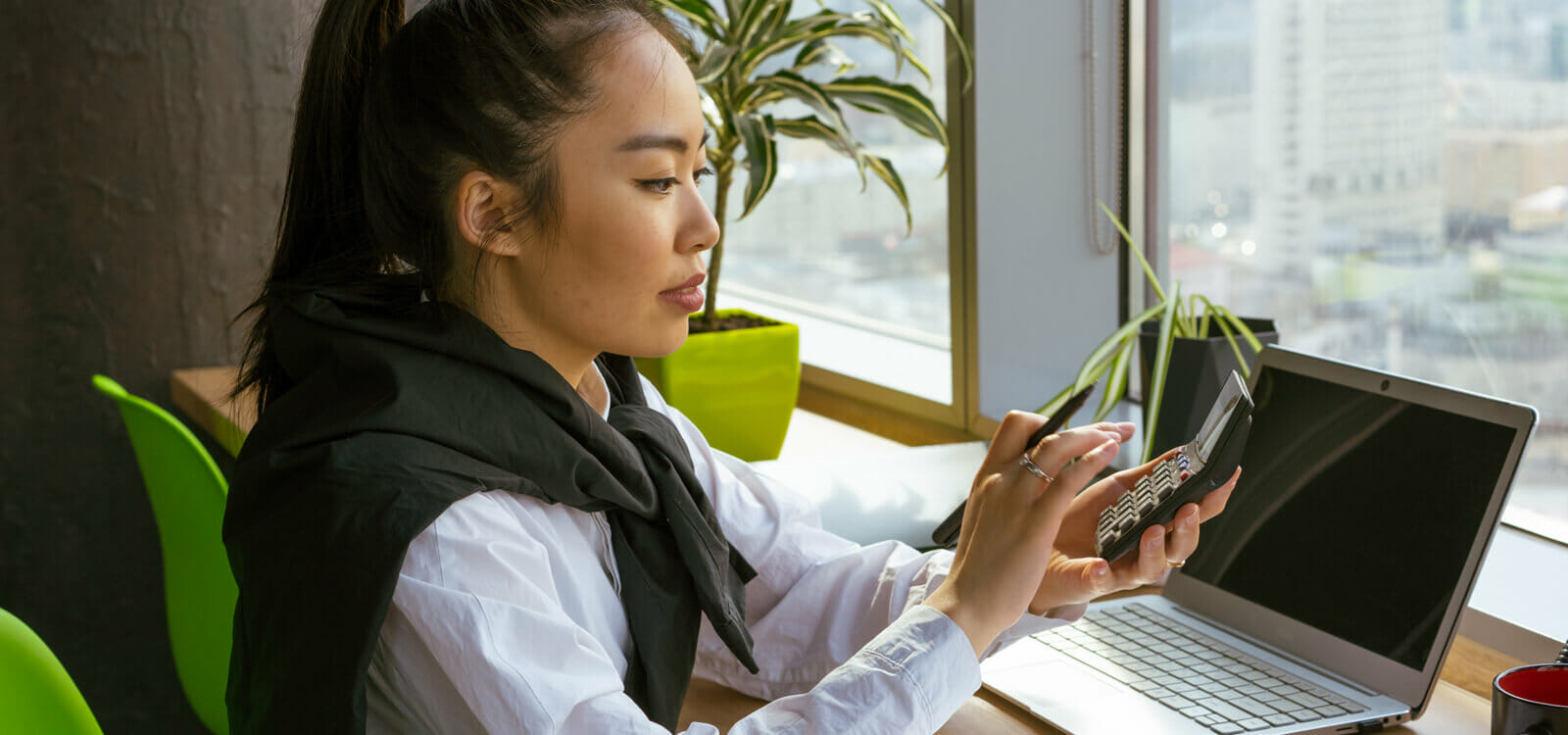 Accounting student working with a calculator and laptop.