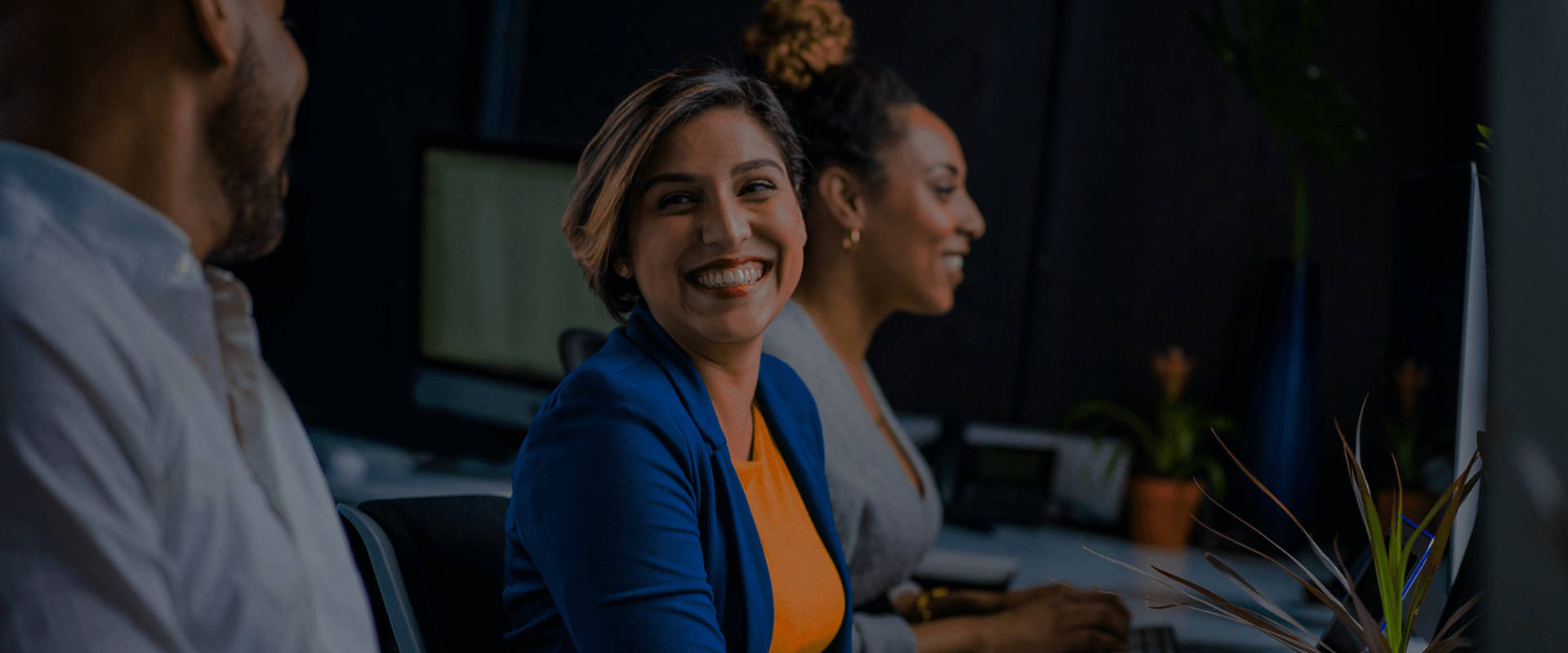 Business professionals in a meeting and a woman is smiling at a colleague.