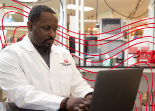 Clinical laboratory scientist working on a laptop in a lab setting.
