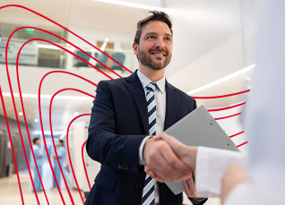 Professional in a suit shaking hands with a healthcare worker in a clinical environment.