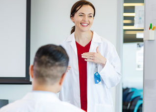 Nurse wearing white lab coat and red scrubs teaching a group class