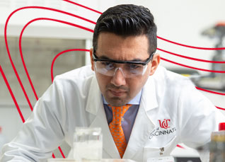 Researcher in safety glasses examining samples closely in a laboratory.