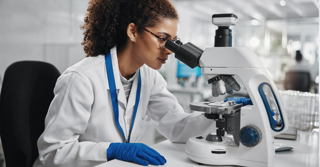 Clinical chemist looking into a microscope.