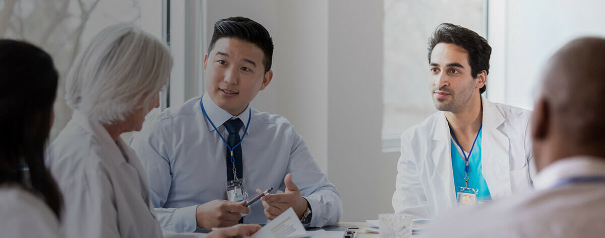Five public health professionals are in a meeting with one speaking to the rest of the group.