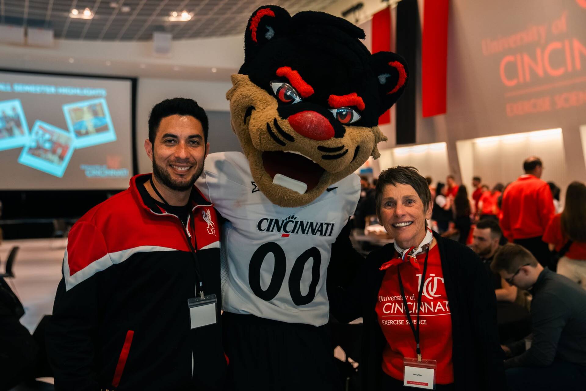 The Bearcat poses with his arm around two people at an exercise science convention.
