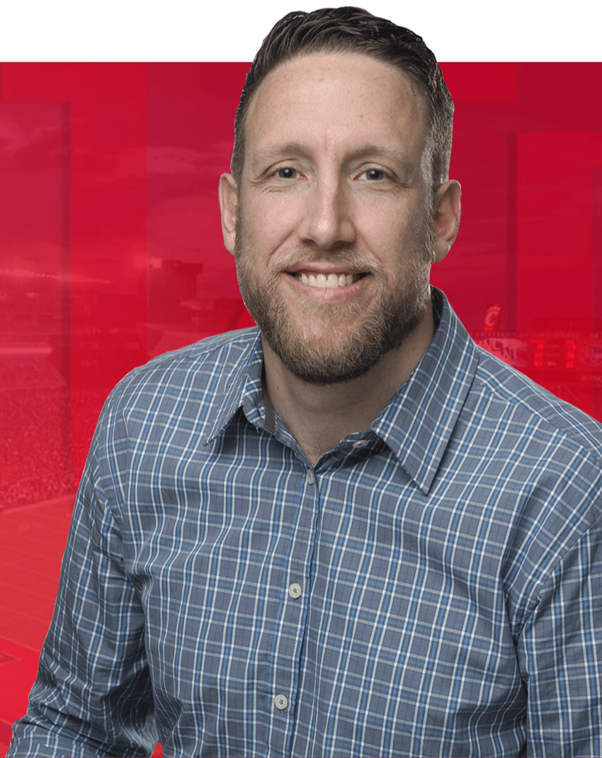 A UC sports administrator professor smiles at the camera.