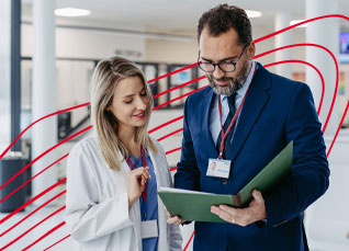 Healthcare leader and clinician reviewing a file together in a hospital hallway.