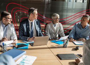 Healthcare administrators reviewing reports and data around a conference table during a team meeting.