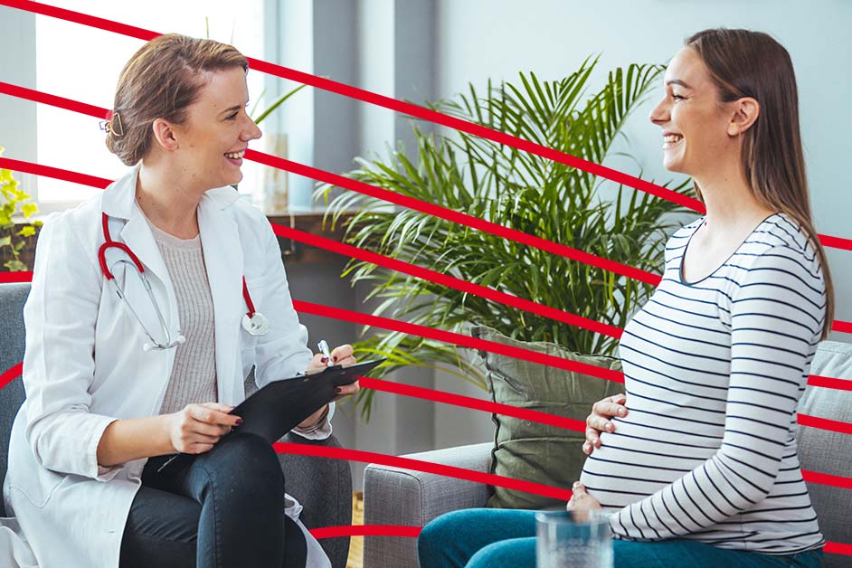 An image of a nurse midwife speaking with a pregnant woman while both are sitting on a grey sofa.