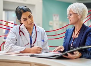 Healthcare professional and administrator reviewing documents together at a hospital desk.