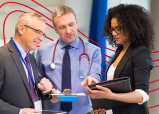 Healthcare executives and a clinician reviewing documents together during a professional meeting.