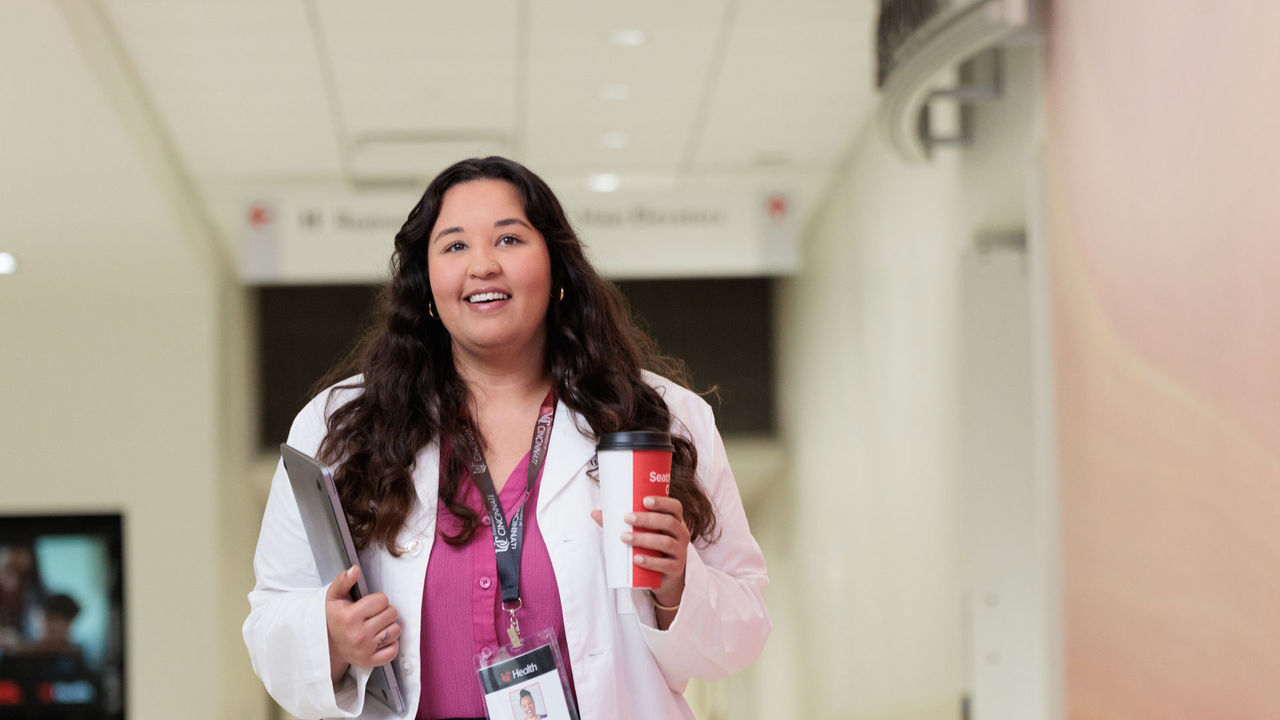 A University of Cincinnati Online student carries a laptop as she works a clinical