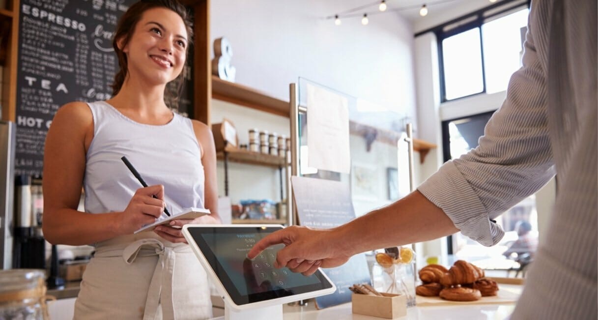 Woman behind counter at cafe take a customer's order