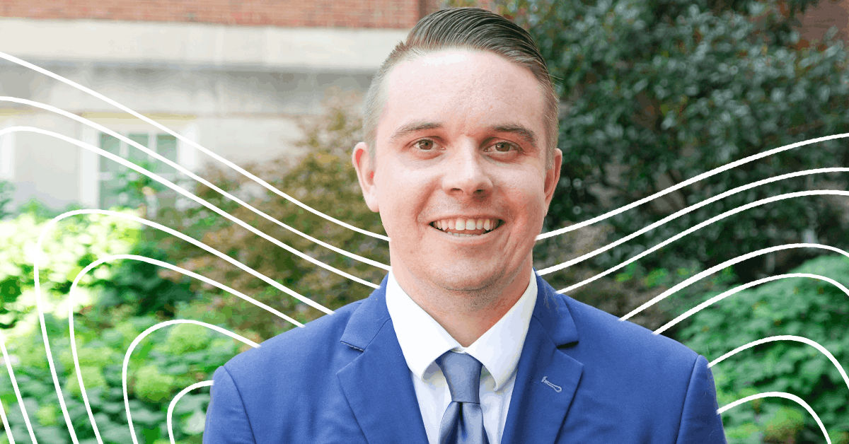 Dr. Nick Lindgren, a professor of behavior analysis at UC Online, stands in front of an outdoor garden background on UC's campus.