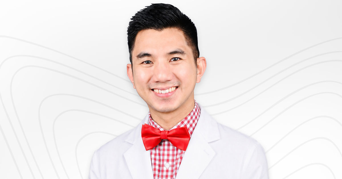 Headshot of Cecil wearing a white lab coat over a red plaid top and red bowtie. 