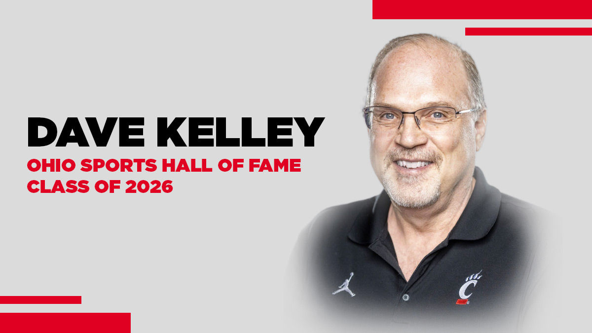 A headshot of Dr. David Kelley, UC Online Professor of Sport Administration. He wears a black UC Athletics polo. He is white, has gray short hair, and wears thin glasses.