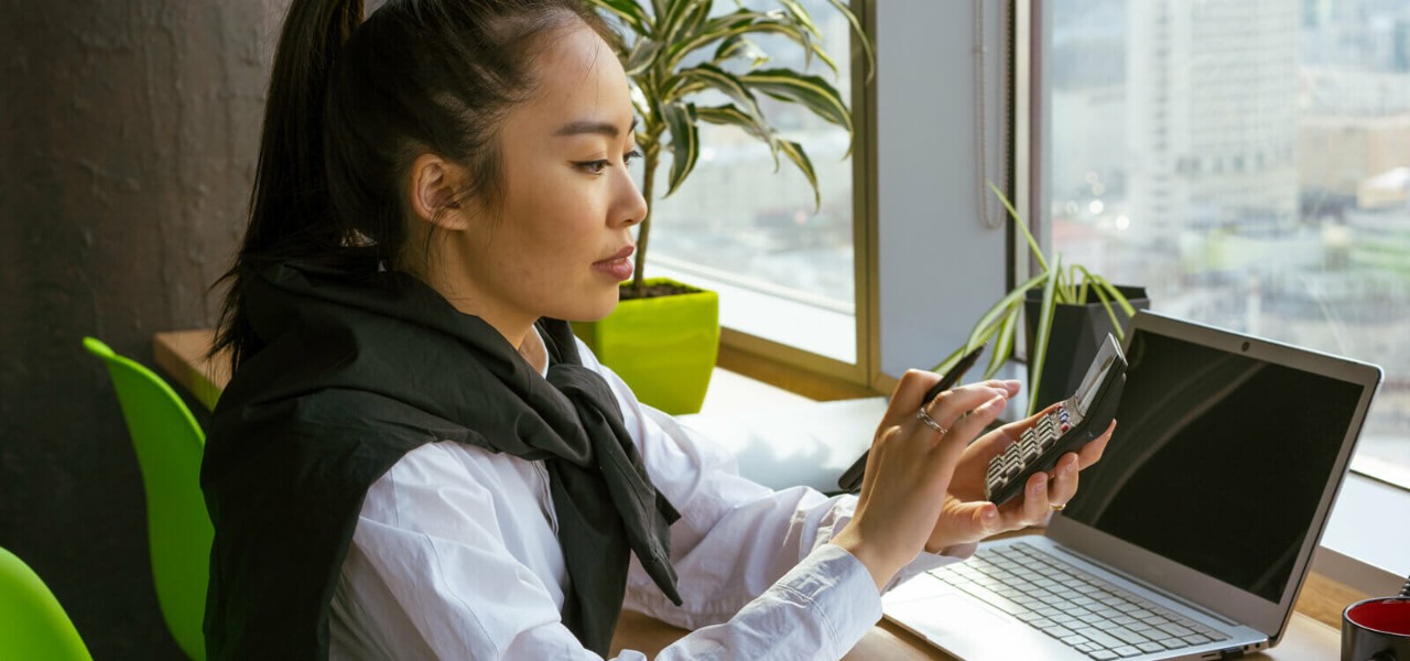 Accounting student working with a calculator and laptop.