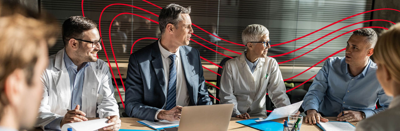 Four Health Informatics Professionals looking at a tablet while sitting down in a meeting room.