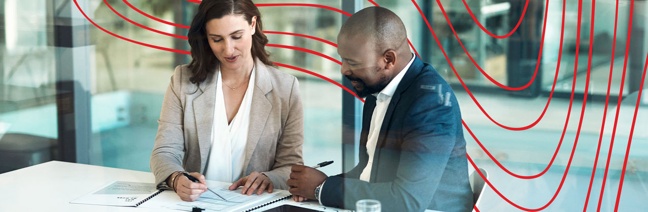 Two professionals walking down a hallway discussing legal documents, representing students in the Master of Legal Studies program.