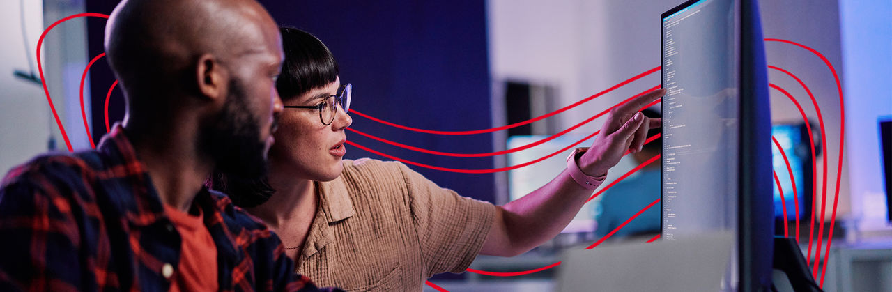Two professionals review code and technical information on a large monitor, collaborating on artificial intelligence solutions.