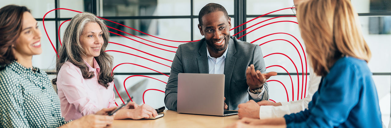 A professional leads a financial discussion with colleagues, reviewing data and insights on a laptop during a meeting.
