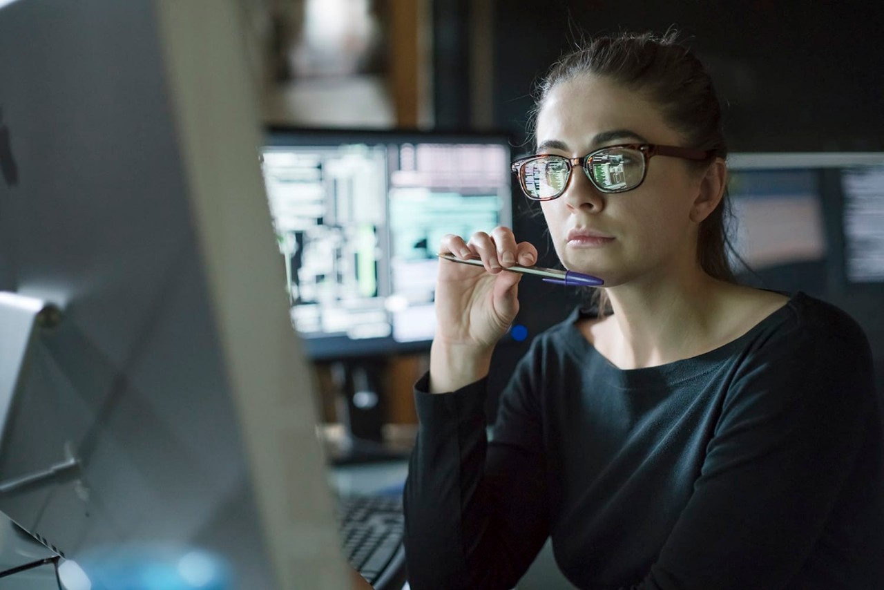 Woman Information systems specialist brainstorming and analyzing data on a laptop in a data center.