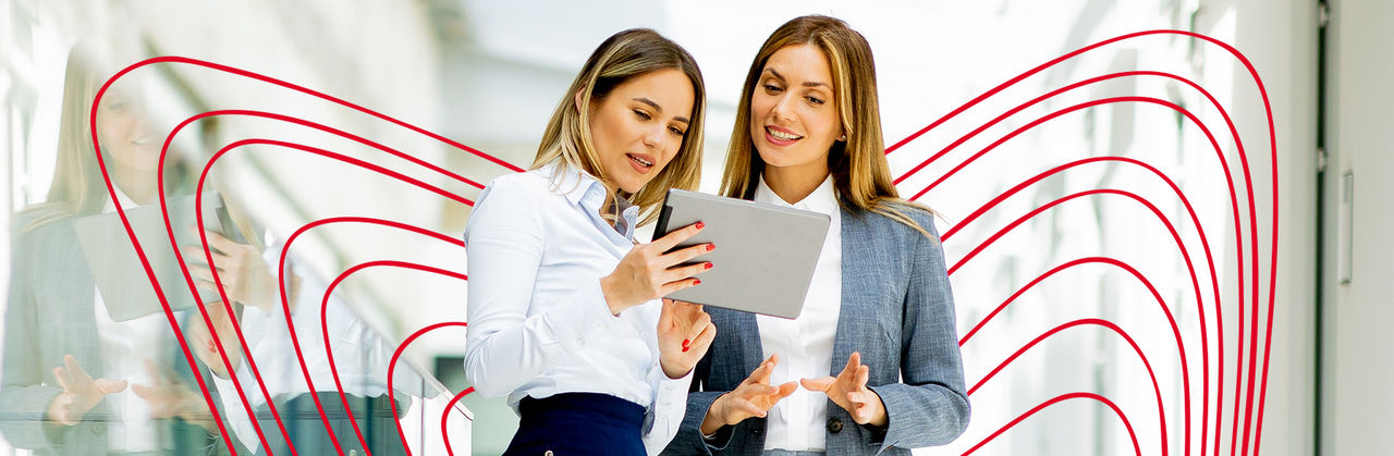 Two professionals review marketing performance data on a tablet, discussing strategy and campaign results.