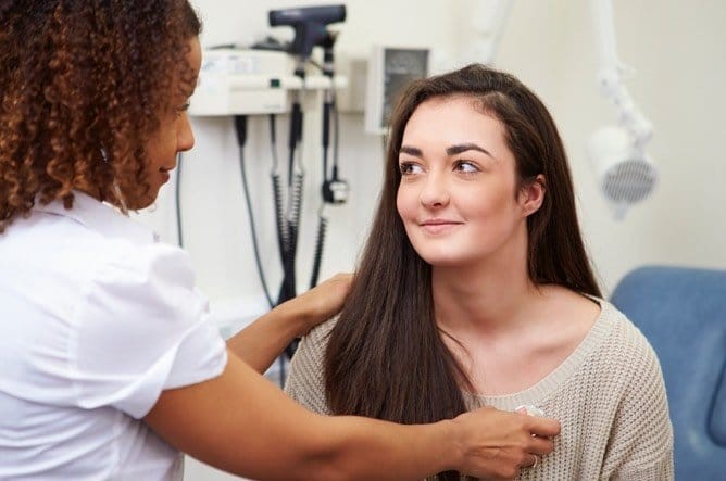 Women's Health Nurse Practitioner checking patient's breathing