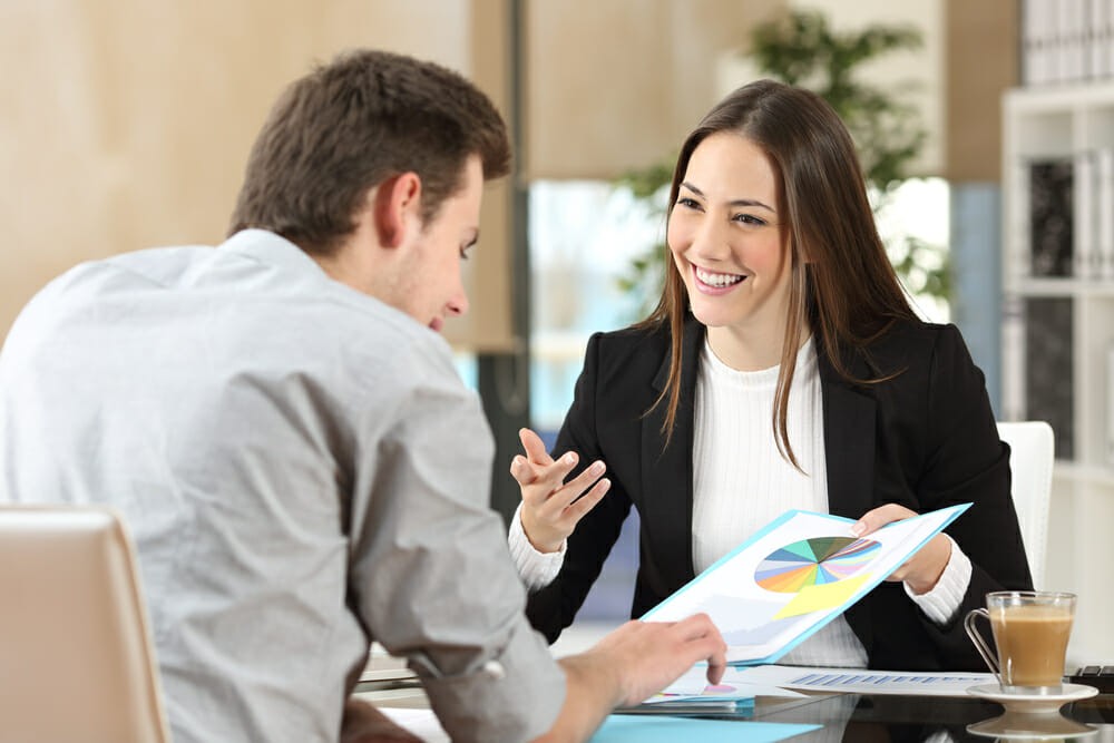 Businesspeople smiling coworking commenting and showing growth graphic and taking a business conversation in an office interior