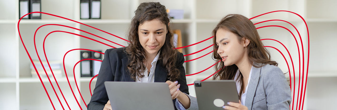 Two professionals review documents and tablet data together, focusing on accounting and financial details.