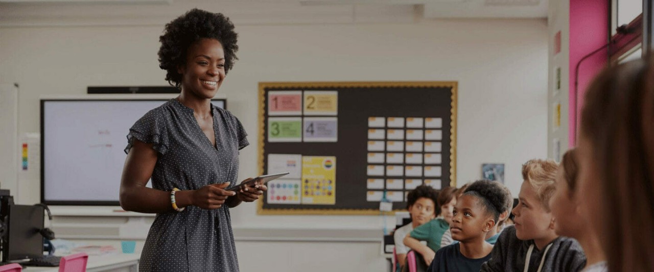A female teacher interacting with students in a classroom.