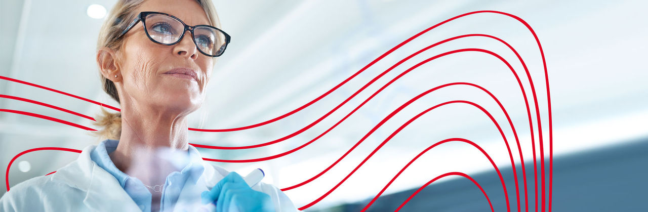 Two pharmaceutical science researchers in lab coats examining a film sheet or test result in a laboratory setting.