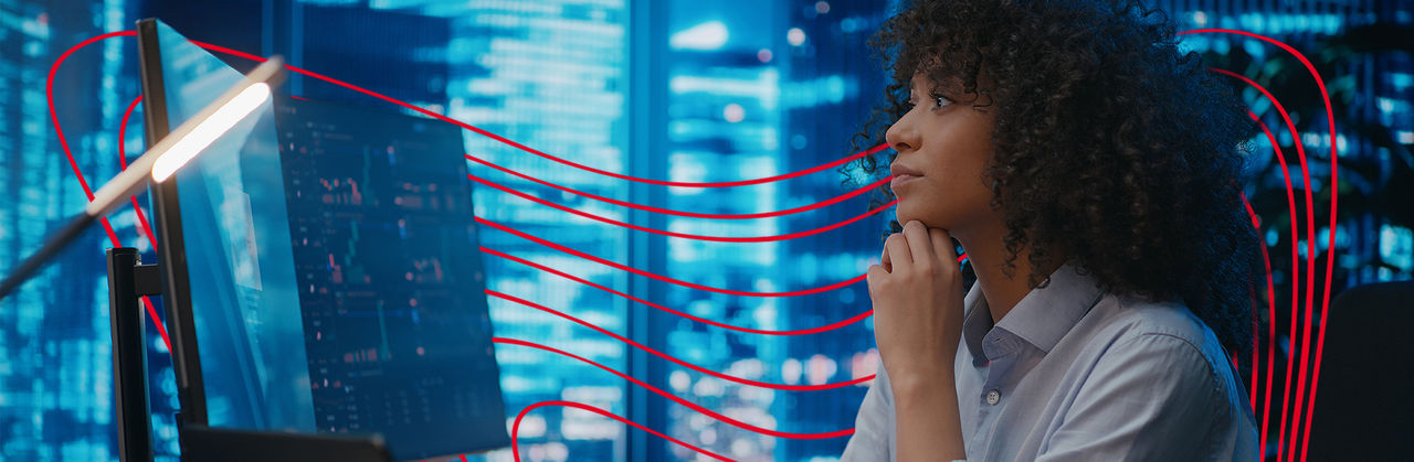 A professional studies financial data on a large digital screen, analyzing trends in a technology-driven environment.