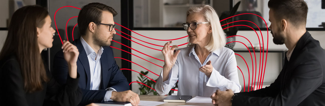 A professional leads a discussion with colleagues, explaining concepts and collaborating during a business analytics meeting.