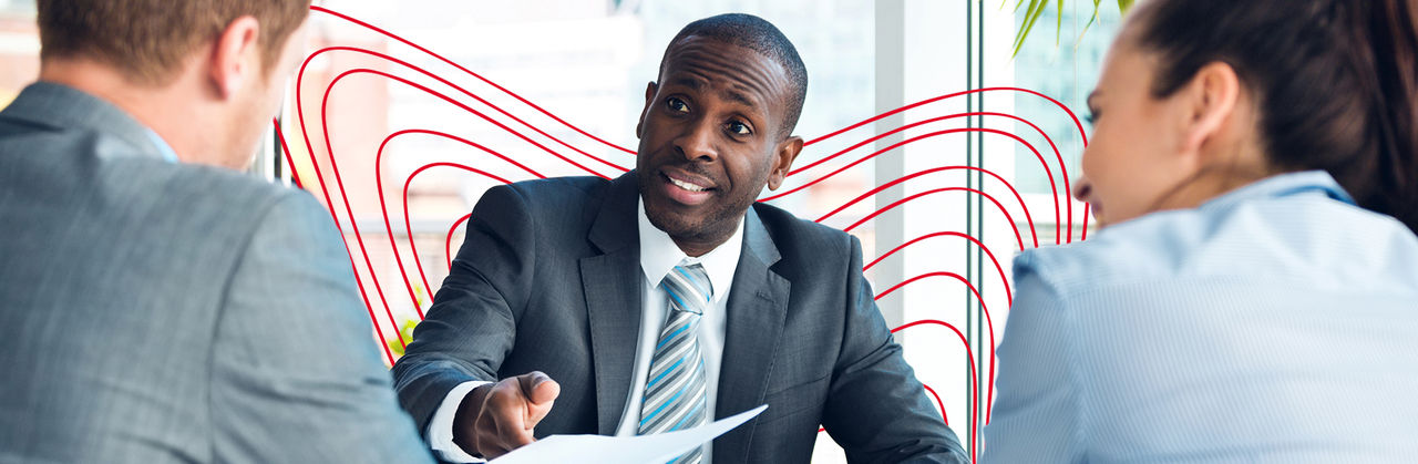 A professional discusses financial documents with two colleagues during a corporate tax planning meeting.