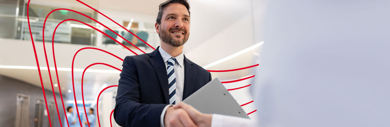 Three health professionals are sitting at a wooden table while one of them writes in a notebook.