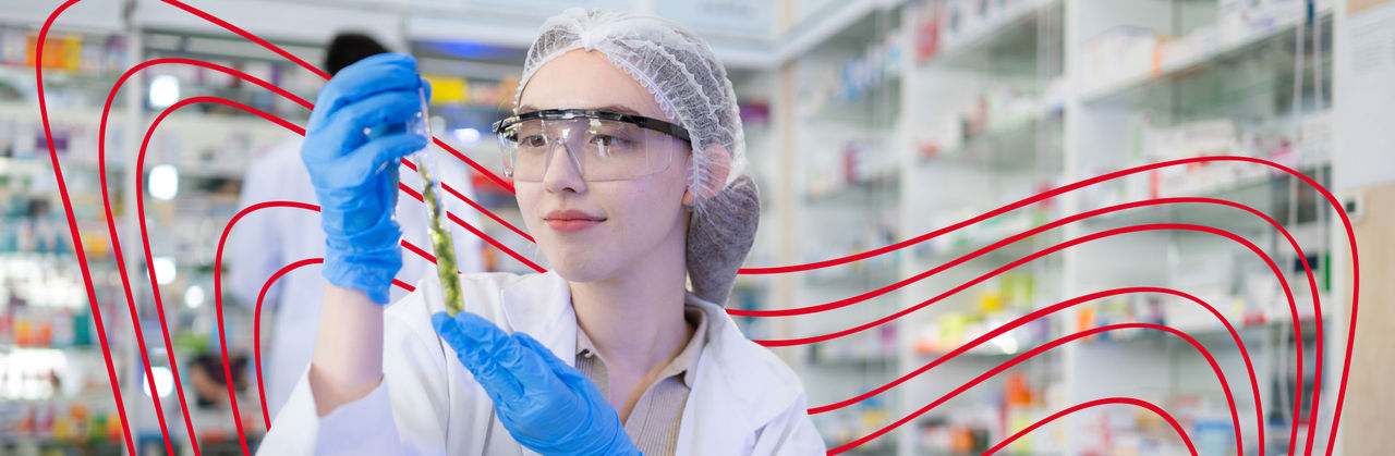 A lab scientist wearing a mask, safety glasses, and gloves handles a syringe and blood samples.